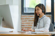 © Songsak C - Happy smiling operator Asian woman customer service agent with headsets working on a computer in a call center.