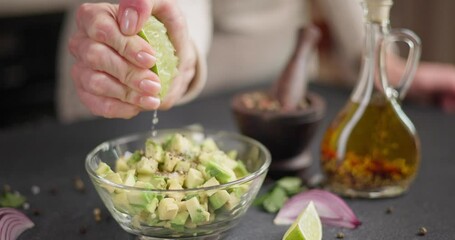 Wall Mural - Woman squeezes fresh lime juice onto Chopped avocado in glass bowl at domestic kitchen