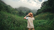 © oatawa - Happy young asian tourist female standing in meadow with mountains and fog at Khao Chong Lom new landmark of Thailand, Carefree woman in fields and stream, Rest on vacation holiday weekend