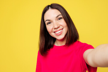 Wall Mural - Close up young smiling happy cheerful woman wear pink t-shirt casual clothes doing selfie shot pov on mobile cell phone isolated on plain yellow orange background studio portrait. Lifestyle concept.