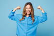© ViDi Studio - Young strong happy woman wear shirt casual clothes showing biceps muscles on hand demonstrating strength power isolated on plain pastel light blue cyan background studio portrait. Lifestyle concept.