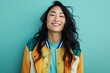 © CogniLens - Portrait of a happy asian woman in her 40s sporting a stylish varsity jacket isolated on soft teal background