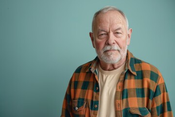 Wall Mural - Portrait of a satisfied caucasian man in his 70s dressed in a relaxed flannel shirt in front of soft teal background