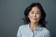 © CogniLens - Portrait of a content asian woman in her 40s donning a classy polo shirt on soft gray background