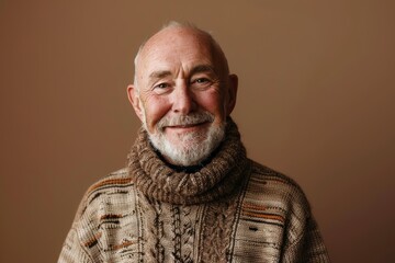 Wall Mural - Portrait of a happy man in his 60s dressed in a warm wool sweater on soft brown background