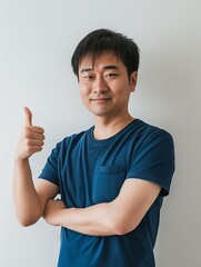 Wall Mural - Asian man showing thumbs up on white background.