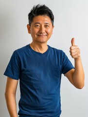 Canvas Print - Asian man giving thumbs up on gray background.