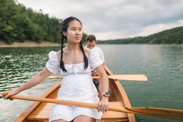 Wall Mural - Young Asian woman posing with paddle in canoe