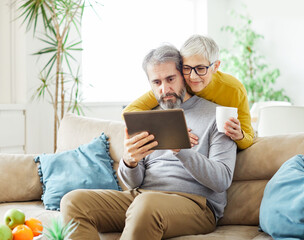 Wall Mural - woman couple senior man happy internet love tablet together mature active elderly retirement computer technology online using caucasian home adult family romance