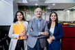 © GAJENDRRA BHATI  - Group of indian corporate businesspeople standing in office. Company staff members in row looking at camera showing unity.