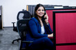 © GAJENDRRA BHATI  - young indian woman sitting on chair talking on phone in office. corporate and workspace concept.
