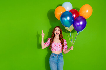 Photo of shiny attractive lady dressed print top holding ballons bunch showing empty space isolated green color background