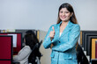 © GAJENDRRA BHATI  - happy young indian woman gesturing thumbs up in office and looking at camera. business, success and corporate concept.