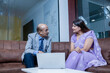 © GAJENDRRA BHATI  - Indian senior businessman with young woman discussing About Company Business Growth Using Laptop. analysis and workplace concept.