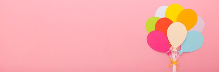 Wall Mural - Bunch of colorful balloon shapes from application paper with white strings and ribbon on light pink table background. Pastel color. Closeup. Wide banner. Empty place for text. Top down view.