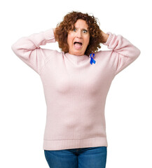 Sticker - Middle ager senior woman wearing changeable blue color ribbon awareness over isolated background Crazy and scared with hands on head, afraid and surprised of shock with open mouth