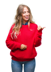 Sticker - Beautiful young blonde woman wearing winter sweater over isolated background smiling with happy face looking and pointing to the side with thumb up.