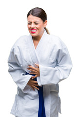 Wall Mural - Young beautiful woman wearing karate kimono uniform over isolated background with hand on stomach because indigestion, painful illness feeling unwell. Ache concept.