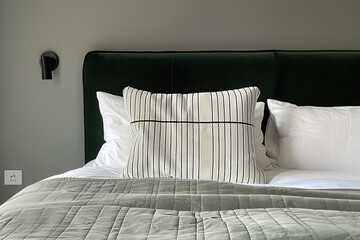 Wall Mural - A striped pillow in white and dark green on the bed, against an olive-green headboard, sits between two larger pillows with gray stripes. The background is a plain grey wall.