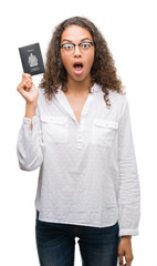 Sticker - Young hispanic woman holding passport of Canada scared in shock with a surprise face, afraid and excited with fear expression