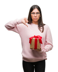 Sticker - Young hispanic woman holding a gift with angry face, negative sign showing dislike with thumbs down, rejection concept