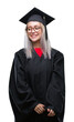 © Krakenimages.com - Young blonde woman wearing graduate uniform over isolated background looking away to side with smile on face, natural expression. Laughing confident.