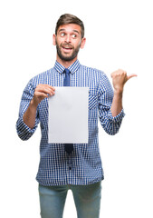 Poster - Young handsome man holding blank paper over isolated background pointing and showing with thumb up to the side with happy face smiling