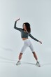 © LIGHTFIELD STUDIOS - A young African American woman in workout clothes poses against a white backdrop, showcasing her athleticism and fitness.