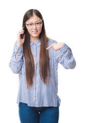 Wall Mural - Young Chinese woman over isolated background speaking on the phone with surprise face pointing finger to himself