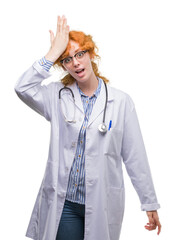 Sticker - Young redhead woman wearing doctor uniform surprised with hand on head for mistake, remember error. Forgot, bad memory concept.