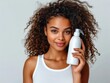 © Johannes - closeup of beautiful young model woman with curly hair holding bottle of shampoo or conditioner hair product. Mock up, advertising for care and beauty hair product. Concept promotion cosmetic product