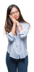 Sticker - Young asian business woman wearing glasses over isolated background sleeping tired dreaming and posing with hands together while smiling with closed eyes.