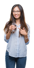 Canvas Print - Young asian woman drinking a glass of water over isolated background very happy pointing with hand and finger