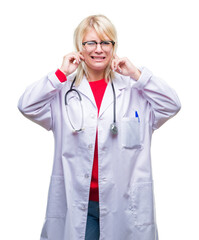 Poster - Young beautiful blonde doctor woman wearing medical uniform over isolated background covering ears with fingers with annoyed expression for the noise of loud music. Deaf concept.