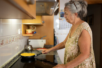 Senior Woman Cooking Spanish Tortilla in Kitchen