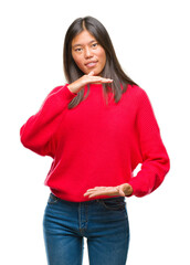 Canvas Print - Young asian woman wearing winter sweater over isolated background gesturing with hands showing big and large size sign, measure symbol. Smiling looking at the camera. Measuring concept.