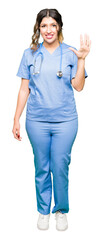 Wall Mural - Young adult doctor woman wearing medical uniform showing and pointing up with fingers number five while smiling confident and happy.