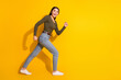 © deagreez - Full body photo of attractive teen woman running fast dressed stylish khaki clothes isolated on yellow color background