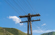 © Sergei - Telegraph pole. Wires of overhead telephone and telegraph communication lines on a wooden pole in a mountainous area. Telecommunications landscape against the backdrop of green mountains and blue sky.