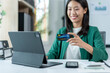 © Wasana - A woman is holding a credit card in front of a computer