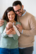© NDABCREATIVITY - Smiling mother and father holding their newborn baby daughter at home
