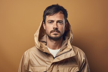 Sticker - Portrait of a glad man in his 30s wearing a lightweight packable anorak in front of soft brown background