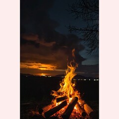 As darkness envelops the night, a crackling bonfire emerges, casting an enchanting glow of orange and yellow flames against the backdrop of the darkened sky