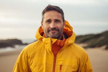 Sticker - Portrait of a glad man in his 40s wearing a windproof softshell isolated in sandy beach background