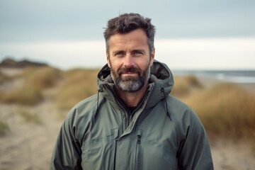 Wall Mural - Portrait of a glad man in his 40s wearing a windproof softshell over sandy beach background