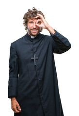 Poster - Handsome hispanic catholic priest man over isolated background doing ok gesture with hand smiling, eye looking through fingers with happy face.