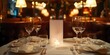 © Pixel Perfect - White Blank Card on Elegant Restaurant Table for Custom Menu Designs at Weddings and Special Events, Blank Card for Menu Design Surrounded by Wine Glasses and Fine Dishes in an Upscale Restaurant