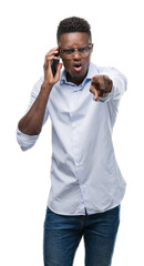 Poster - Young african american man using smartphone pointing with finger to the camera and to you, hand sign, positive and confident gesture from the front