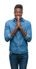 Poster - Young african american man over isolated background praying with hands together asking for forgiveness smiling confident.