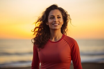 Wall Mural - Portrait of a blissful indian woman in her 30s sporting a breathable mesh jersey on vibrant beach sunset background